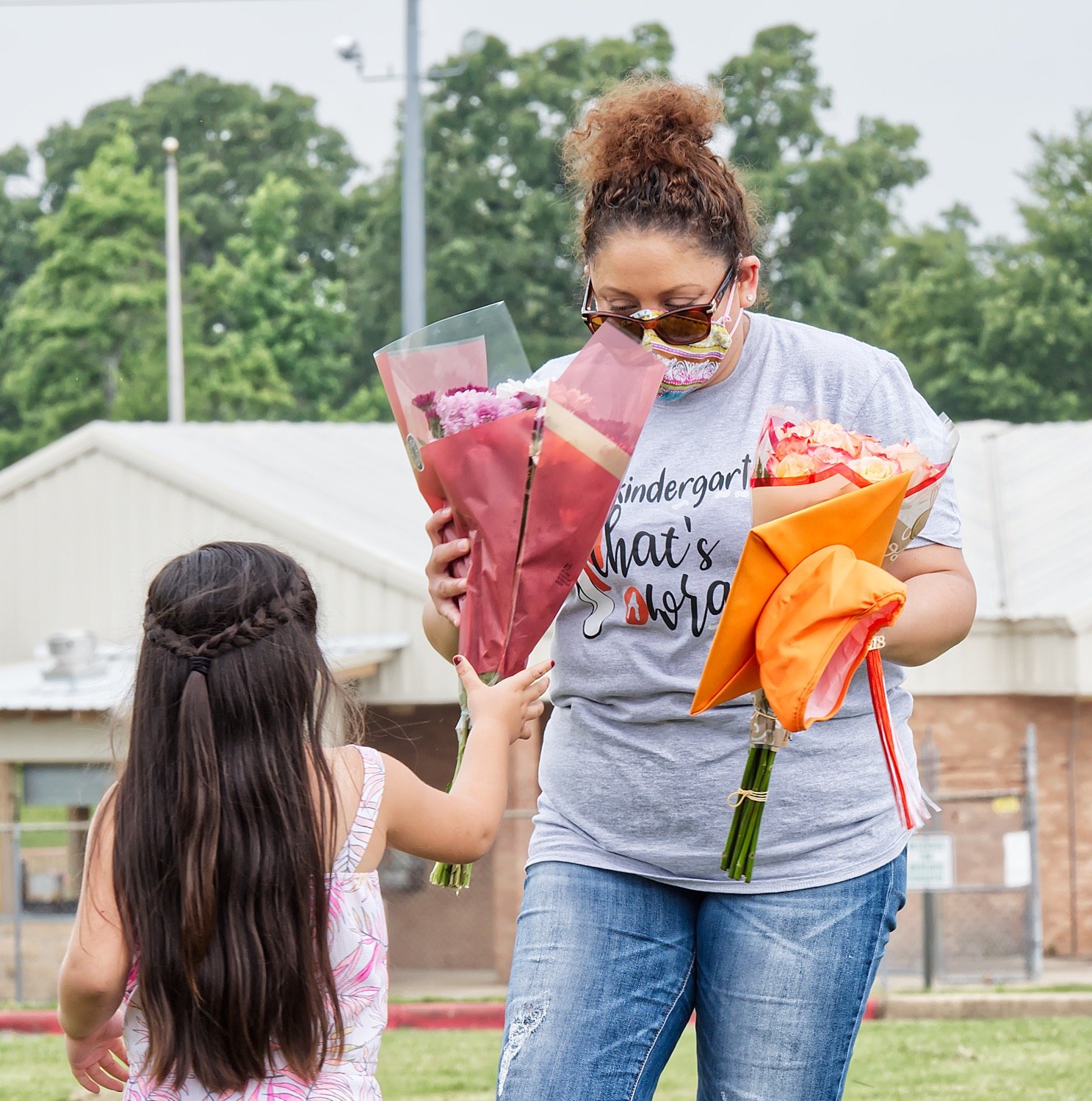 Mineola kindergarten teacher Raquel Palma gets flowers from Diana Galaz Valenzuela at last week’s drive through graduation.
